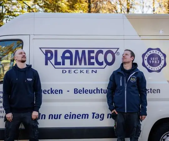 Zwei Handwerker stehen vor einem Plameco-Decken-Montagefahrzeug mit Werbebeschriftung.