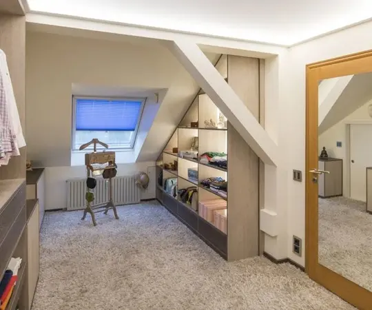 Moderner begehbarer Kleiderschrank mit Teppichboden und Dachschräge in heller Dachgeschosswohnung.